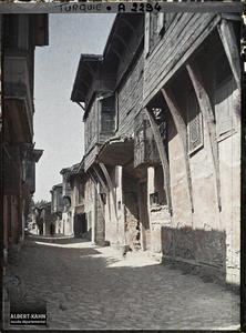 Turquie d'Asie, Scutari, Une rue à maisons de bois près de Yéni - Validé Djami. Rue pavée, bordée de maisons en dur à moucharabiehs de bois